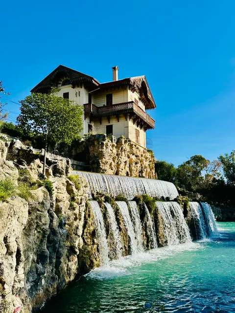 A waterfall below a hillside house, France