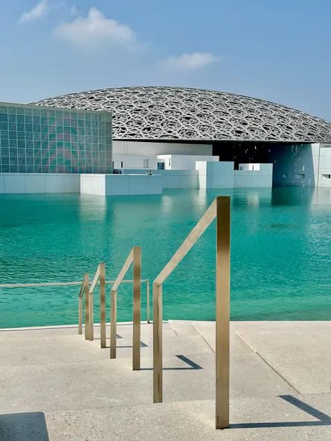 The Louvre Abu Dhabi beside turquoise water, United Arab Emirates